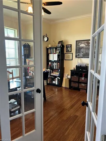 Office area with crown molding, french doors, ceiling fan, and dark wood-type flooring