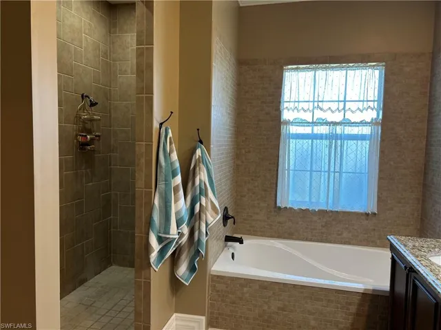 Bathroom featuring vanity and tiled bath