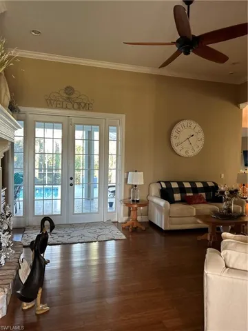 Living room featuring ceiling fan, french doors, crown molding, and dark hardwood / wood-style floors