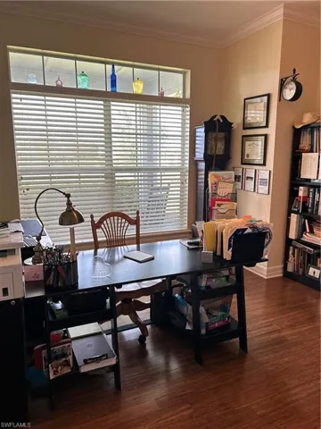 Office area with dark hardwood / wood-style flooring and crown molding