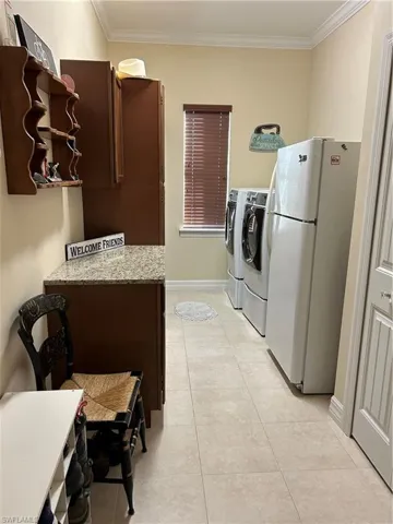 Laundry area featuring light tile patterned floors and crown molding