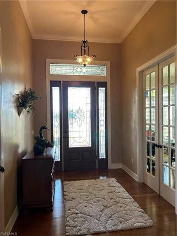 Entrance foyer featuring french doors, dark hardwood / wood-style floors, an inviting chandelier, and ornamental molding