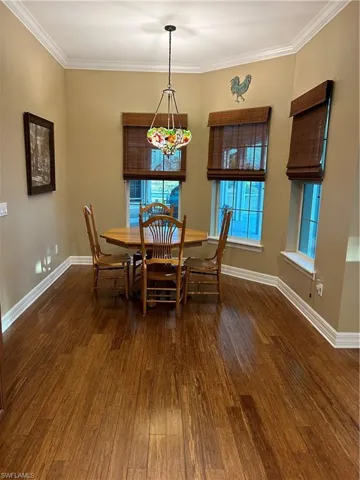 Dining space with dark hardwood / wood-style floors, a wealth of natural light, and ornamental molding
