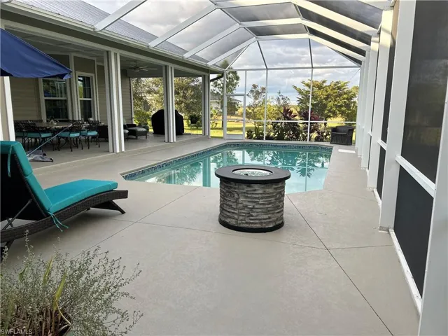 View of swimming pool with glass enclosure, ceiling fan, and a patio area