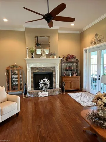 Unfurnished room with ceiling fan, french doors, hardwood / wood-style floors, a fireplace, and ornamental molding