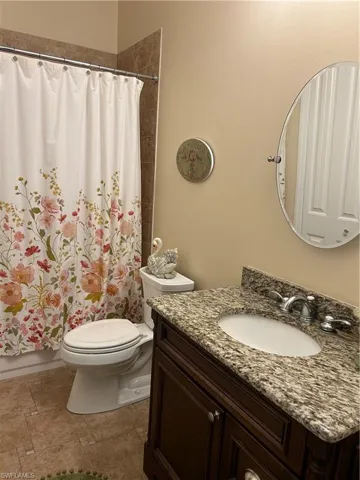 Full bathroom featuring vanity, shower / bath combination with curtain, and toilet