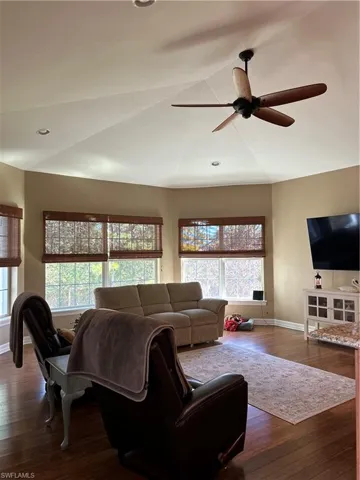 Living room with lofted ceiling, ceiling fan, and dark hardwood / wood-style floors
