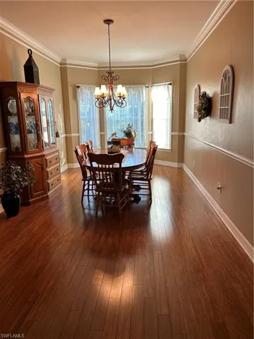 Dining room with crown molding, dark hardwood / wood-style flooring, and a notable chandelier