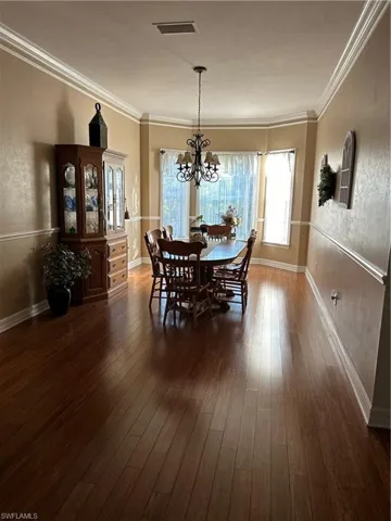 Dining area with a chandelier, dark hardwood / wood-style flooring, and ornamental molding
