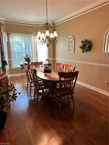 Dining room with dark hardwood / wood-style flooring, ornamental molding, and a notable chandelier