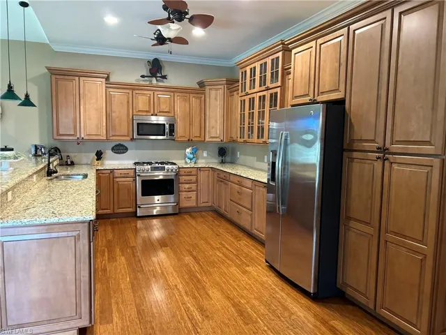 Kitchen with sink, crown molding, ceiling fan, decorative light fixtures, and stainless steel appliances