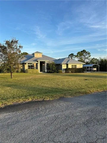 View of front facade with a carport and a front yard