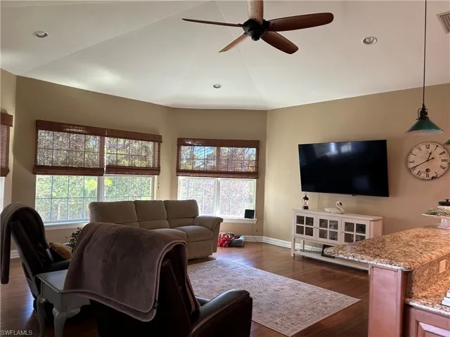 Living room with ceiling fan and dark wood-type flooring