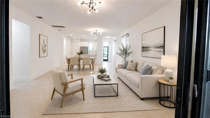 Spacious living area featuring light-toned tile flooring throughout, recessed lighting, and a contemporary ceiling fixture