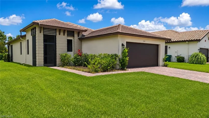 Contemporary stucco exterior featuring a tile roof, an integrated two-car garage with a dark brown door, and a paver driveway