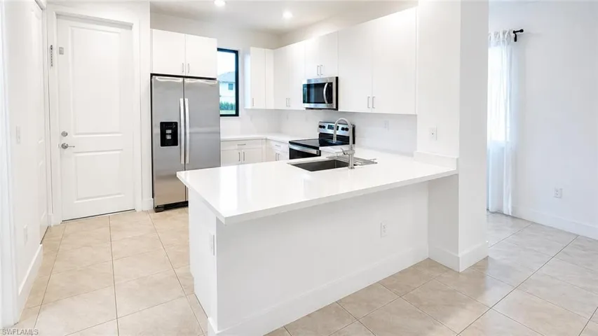 Modern kitchen featuring white cabinetry and light-toned tile flooring