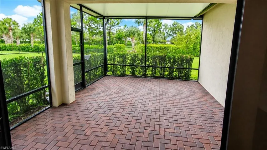 Screened patio featuring a brick paver floor, stucco exterior wall, and surrounding green landscaping
