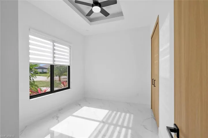Unfurnished room featuring ceiling fan, a wealth of natural light, and a raised ceiling