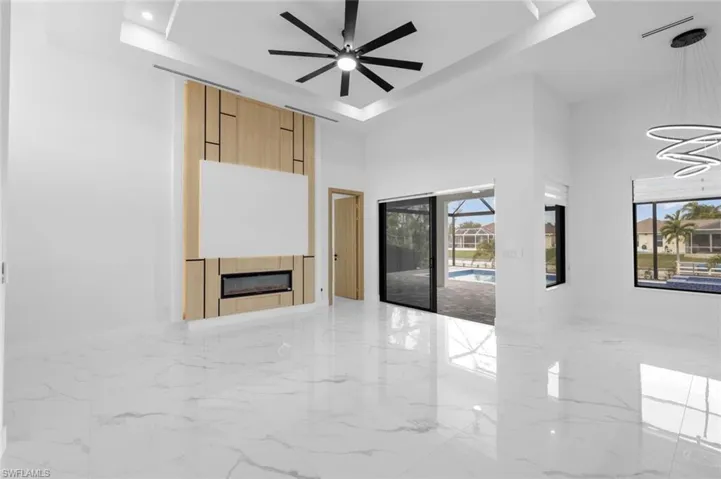 Unfurnished living room with ceiling fan, a tray ceiling, and a tiled fireplace