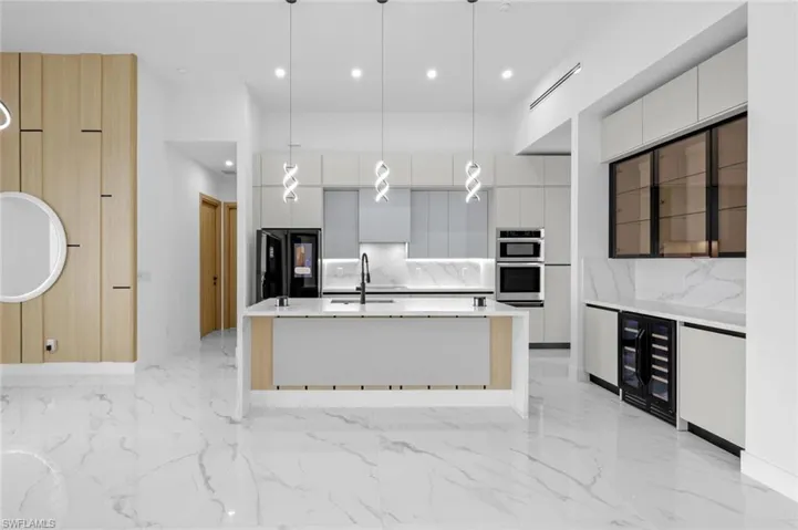 Kitchen featuring white cabinetry, black refrigerator, and pendant lighting