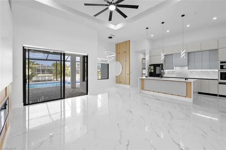 Kitchen with decorative light fixtures, an island with sink, decorative backsplash, sink, and gray cabinets