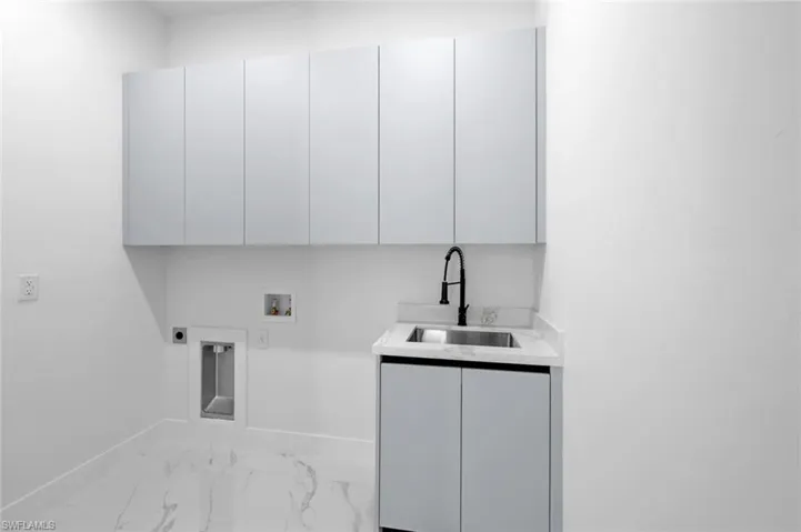Clothes washing area featuring washer hookup, sink, electric dryer hookup, and cabinets