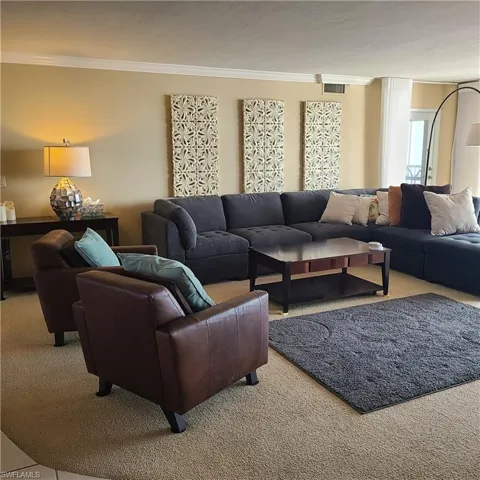 Living room with crown molding and light colored carpet