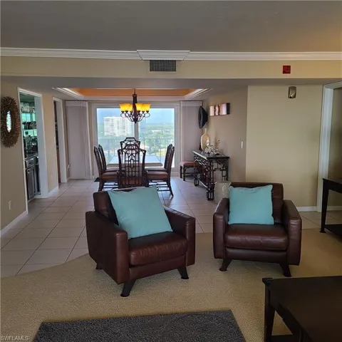 Living room featuring crown molding, light tile patterned floors, and an inviting chandelier