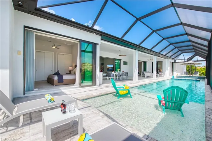 Screened pool enclosure featuring a sun shelf with in-pool seating, ample deck space, and direct access to an interior room with sliding glass doors