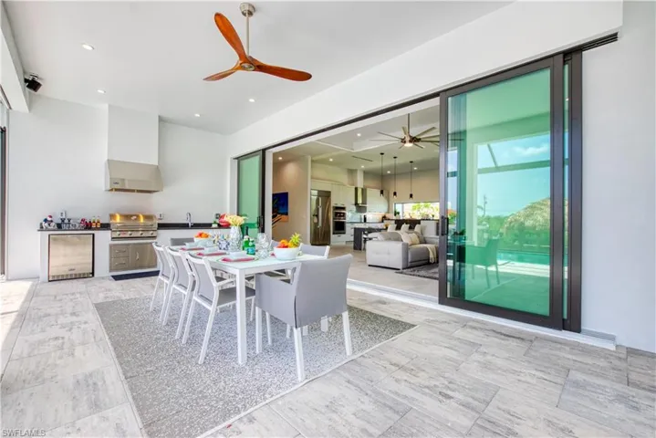 Covered outdoor kitchen and dining area featuring stainless steel appliances, a built-in grill, and a ceiling fan