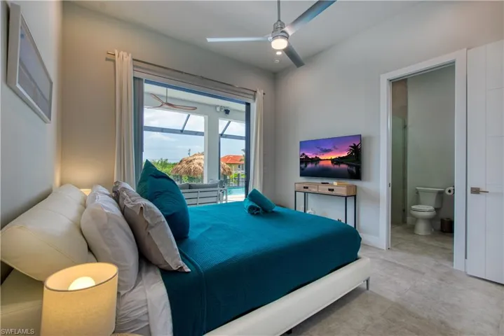 Bedroom featuring light gray walls, a modern ceiling fan, and large sliding glass doors opening to a screened patio with a pool
