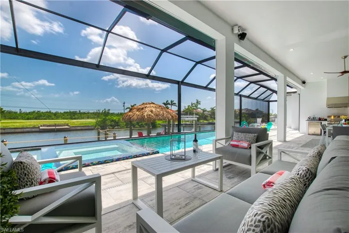 Expansive screened lanai featuring an outdoor kitchen, inground pool and spa, and canal frontage
