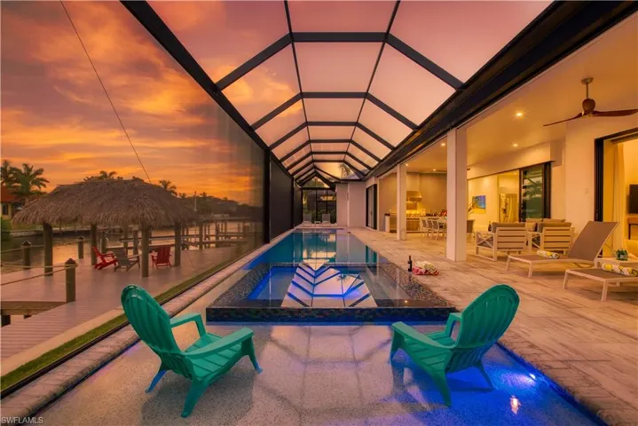 Screened lanai featuring a long swimming pool with integrated spa and underwater lighting