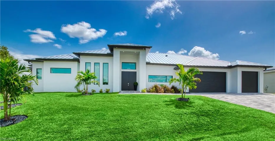 Contemporary architecture featuring a white exterior, dark metal roof, and a meticulously maintained green lawn