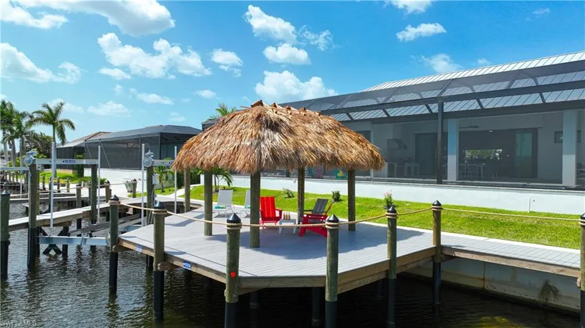 Waterfront dock with a thatched-roof tiki hut, composite decking, and dual boat lifts