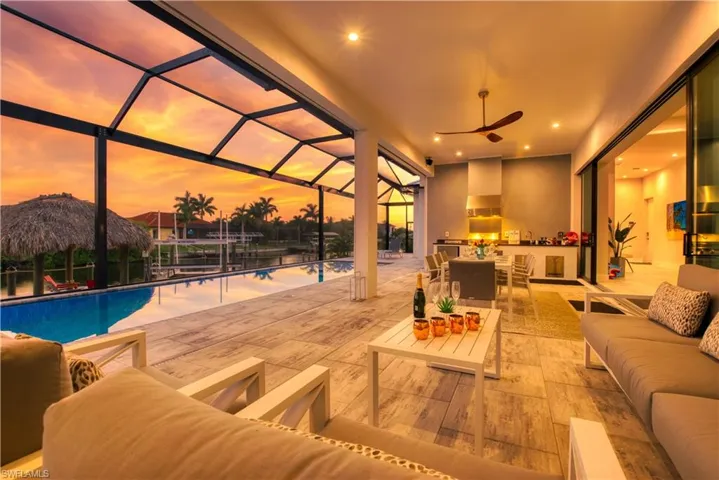 Expansive lanai with a screened enclosure, large swimming pool, and an outdoor kitchen featuring a built-in grill and hood vent