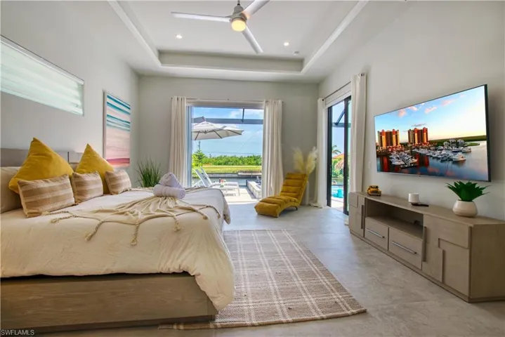 Spacious bedroom featuring contemporary light-toned flooring, tray ceiling with recessed lighting, and a ceiling fan