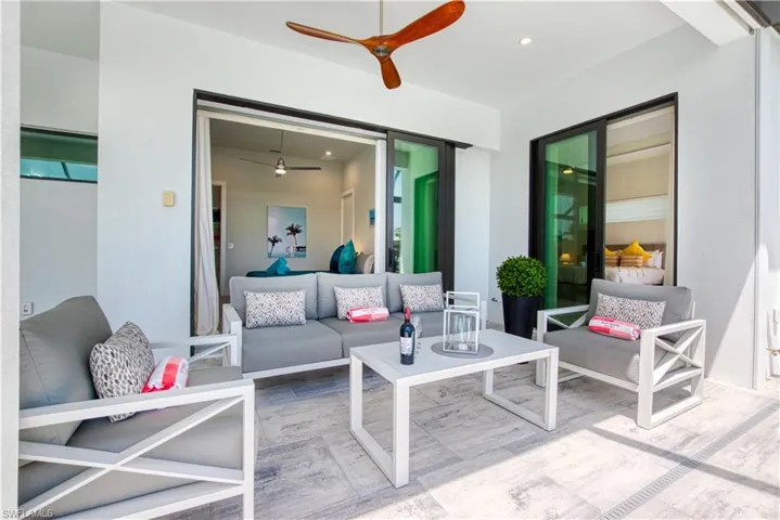 Covered outdoor patio featuring light-toned tile flooring, a wood-blade ceiling fan, and recessed lighting