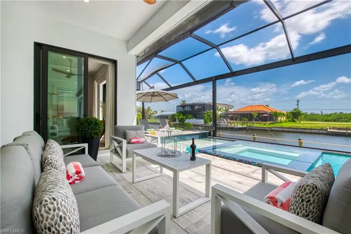 Screened lanai featuring a built-in spa, waterside pool, and canal frontage