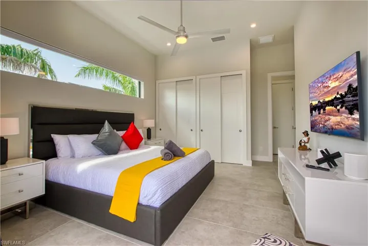 Vaulted ceilings highlight this room featuring a high horizontal window, a ceiling fan with integrated lighting, and light-toned flooring