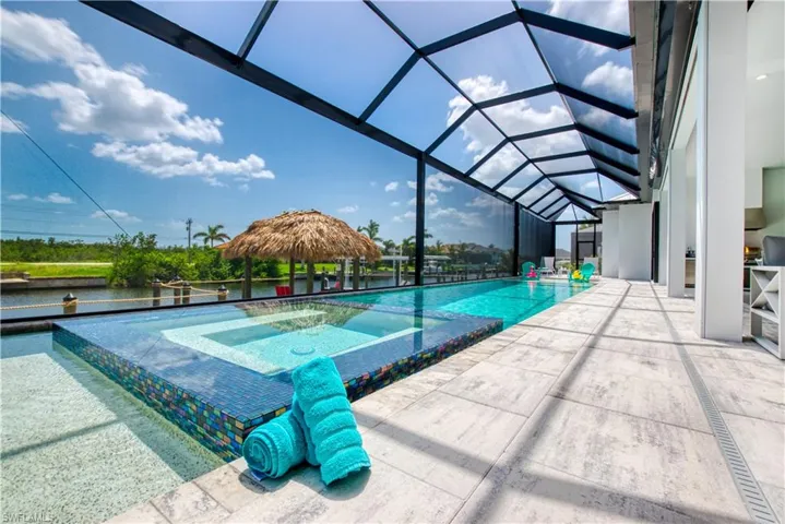 Screened lanai featuring a rectangular pool and integrated spa with mosaic tile accents