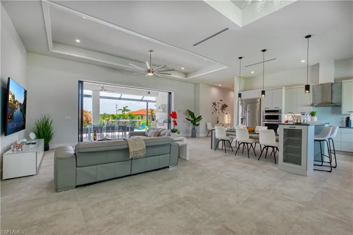 Open-concept living space with large format tile flooring and a tray ceiling
