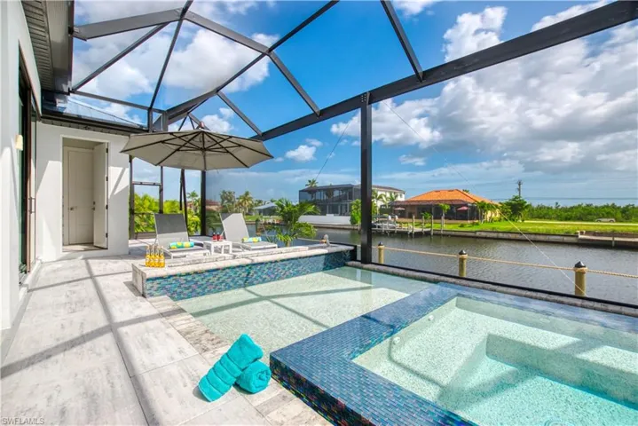 Screened lanai featuring a swimming pool and integrated spa, both with blue mosaic tile accents