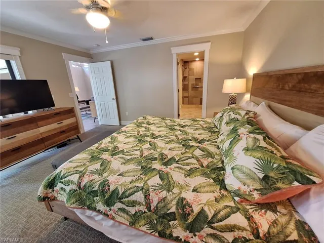 Bedroom with crown molding, dark colored carpet, ceiling fan, and ensuite bath