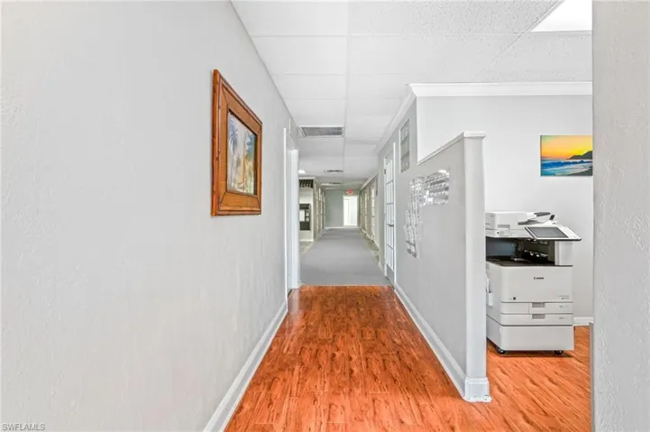 Corridor featuring crown molding, a drop ceiling, and hardwood / wood-style flooring