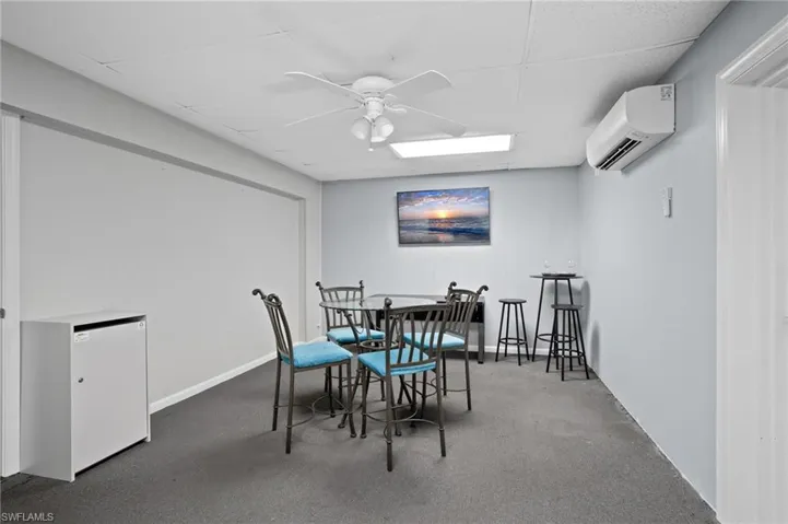 Dining area featuring ceiling fan, a drop ceiling, and a wall mounted air conditioner