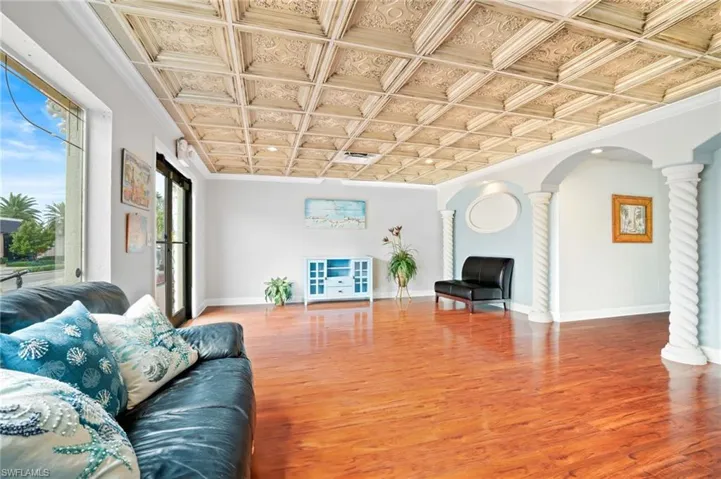 Entry way featuring wood-type flooring, crown molding, coffered ceiling, and decorative columns