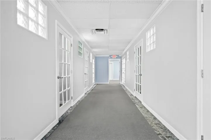 Corridor with a wealth of natural light, a drop ceiling, and french doors