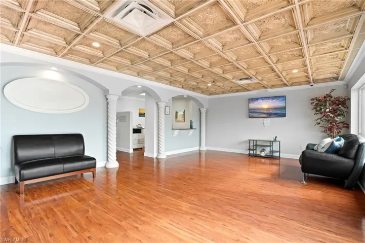 Entry way with decorative columns, wood-type flooring, crown molding, and coffered ceiling