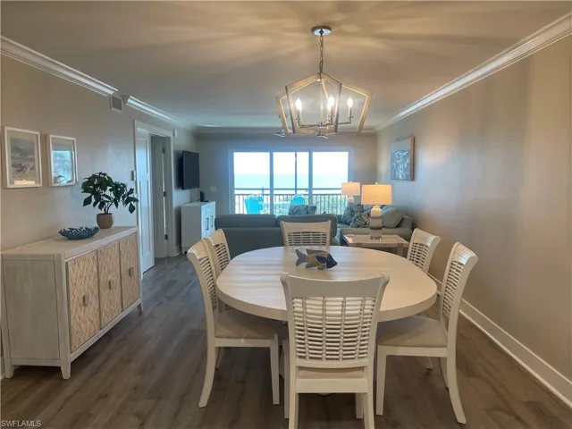 Dining room with ornamental molding, dark wood-type flooring, and a chandelier